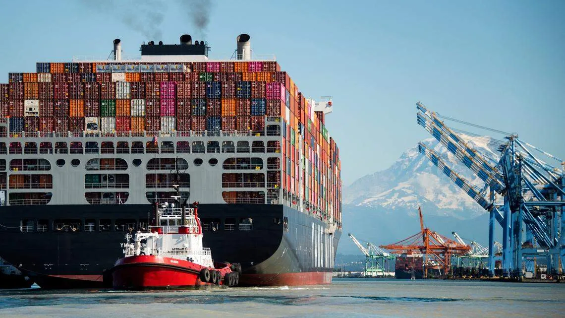 Container vessel and tugboats with Mount Rainier near Tacoma